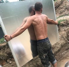 Homme portant un panneau pour l'installation d'une piscine enterrée