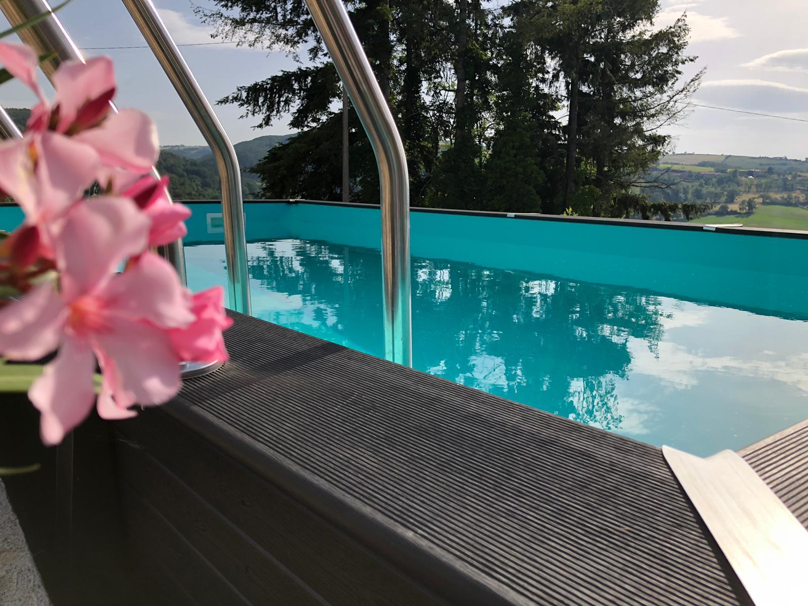 Piscine rectangulaire noire avec des fleurs roses en premier plan